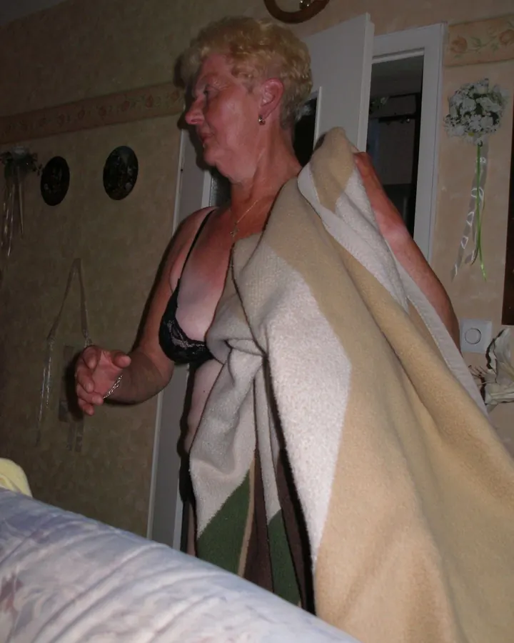 Femme aux cheveux blonds, en robe bleue, posant dans une chambre