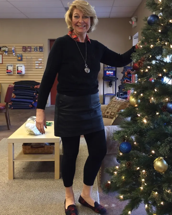 Emma près d'un sapin de Noël, pull noir et jupe cuir