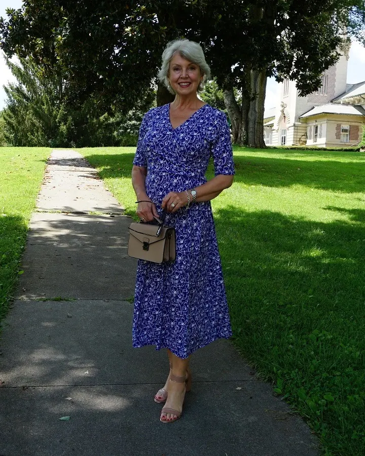 Femme aux cheveux blancs, en robe bleue, posant dans une chambre