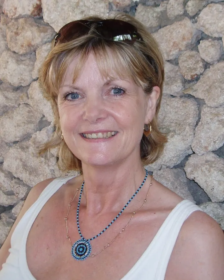 Femme aux cheveux blonds, en robe bleue, posant dans une chambre