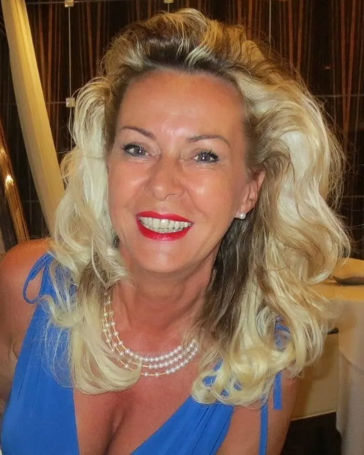 Femme blonde, en robe bleue, souriante, avec des cheveux bouclés, regardant l'appareil photo