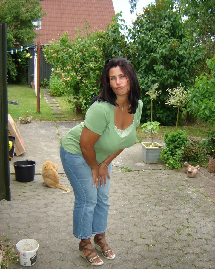 Femme aux cheveux châtains, portant un haut noir, assise sur un canapé noir.